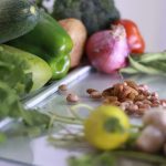 From above of various fresh organic colorful vegetables and nuts placed on glass tabletop in light kitchen