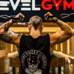 Back view of a muscular man working out in a modern gym, focusing on strength and fitness.